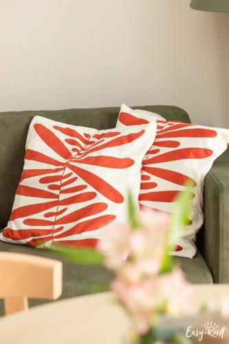 a red and white pillow on a couch at K&K Apartment - Premium z basenem - SeaShell - Easy - Rent Apartments in Łukęcin