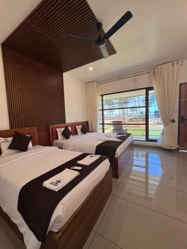 a bedroom with two beds and a ceiling fan at Vista Oceano Beach Resort in Varkala