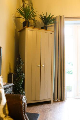 a cabinet with plants on top of it in a living room at Beautiful Cotswold Couples Retreat in Bourton on the Water