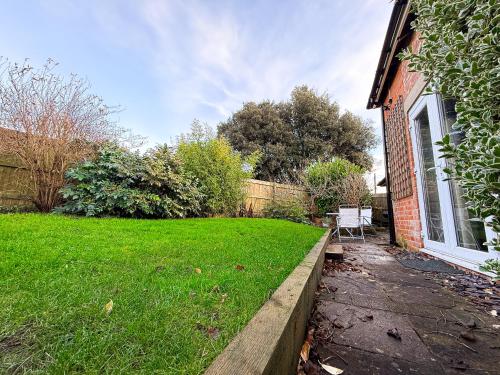 a backyard with a lawn and a house with a chair at Beautiful Cotswold Couples Retreat in Bourton on the Water