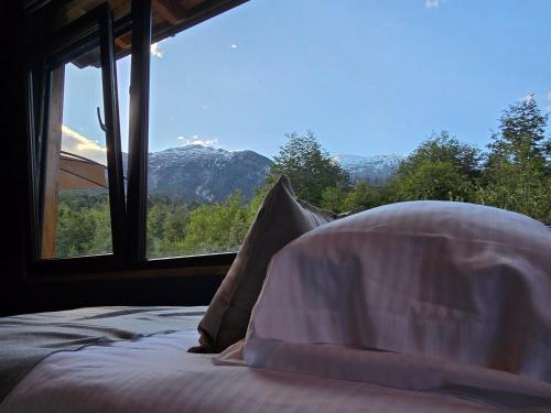 a bed in a room with a view of a mountain at Peuma Lodge Patagonia in Futaleufú