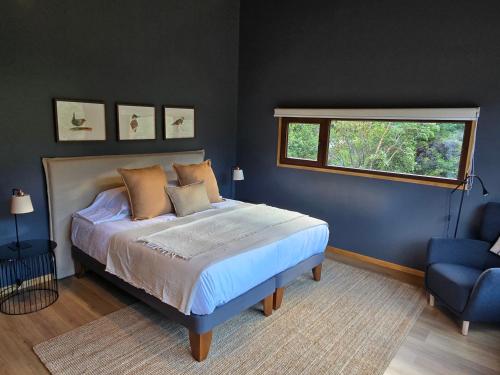a bedroom with a bed and a window and a blue chair at Peuma Lodge Patagonia in Futaleufú
