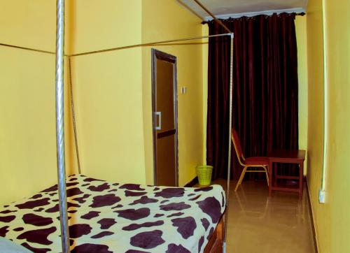 une chambre avec un lit, une table et une chaise dans l'établissement CAJANUS INN KARATu, à Karatu