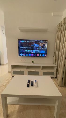 a living room with a white table and a tv at OSI Apartments Powai in Mumbai