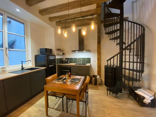 une cuisine avec une table et un escalier en colimaçon dans l'établissement L'Oasis Angevine - Balneo, Sauna, Home Cinema & Parking, à Angers