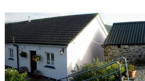 a small white house with a black roof at Bleantis Mountain Cottage in the Comeragh Mountains in Dungarvan