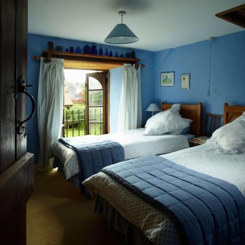 a blue bedroom with two beds and a window at Spindle Cottage Holidays in Radstock