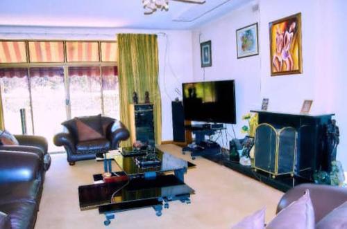 un soggiorno con mobili in pelle e una TV a schermo piatto di Baobab Garden a Harare
