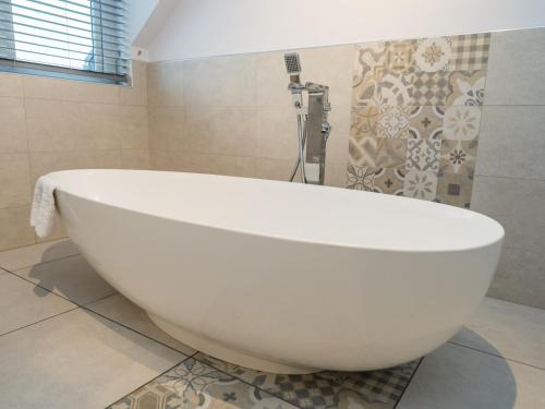 a large white bath tub in a bathroom at Pass the Keys Modern 4-Bed Home Spacious & Comfortable in Pontesbury