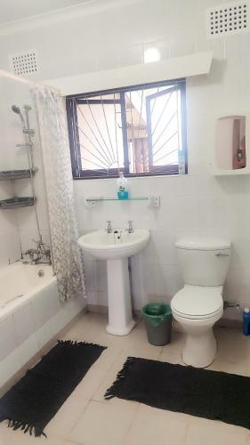 a bathroom with a sink and a toilet and a tub at Pumula on 5th in Pumula