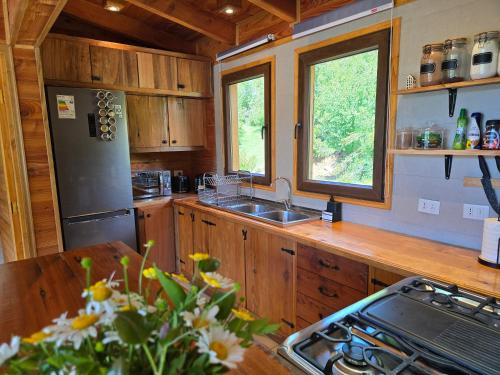 a kitchen with wooden cabinets and a sink and a refrigerator at Peuma Lodge Patagonia in Futaleufú