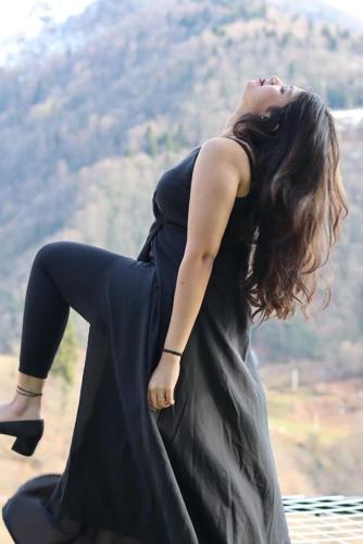 a woman in a black dress sitting on a ledge at Eco cottage sunrise merisi in Merisi