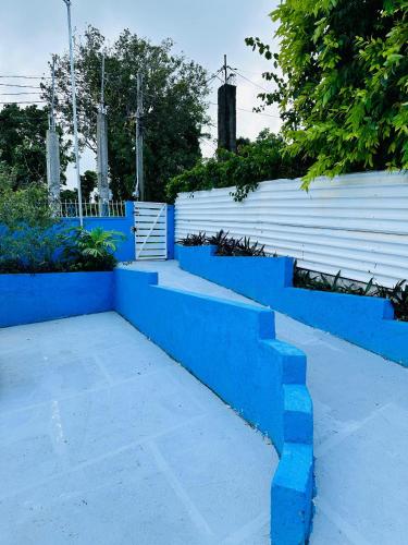a blue retaining wall with steps in front of a fence at Master Room - Ferdie's Place in Port Antonio