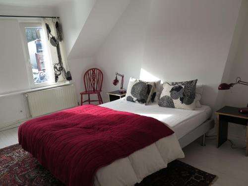 a bedroom with a bed with a red blanket and a window at La Petite Lili in Dinant