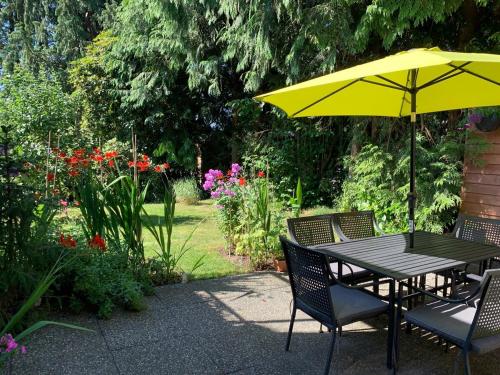 a table and chairs with an umbrella in a garden at Awesome 2BR in Lynn Valley in North Vancouver