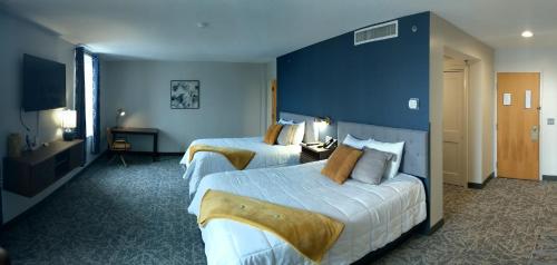 two beds in a hotel room with blue walls at The Northeastland Hotel in Presque Isle