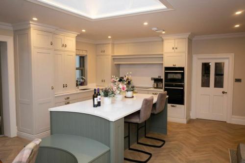 a kitchen with white cabinets and a island with chairs at Private Country Residence Made 4 Luxury Gathering in Newcastle West