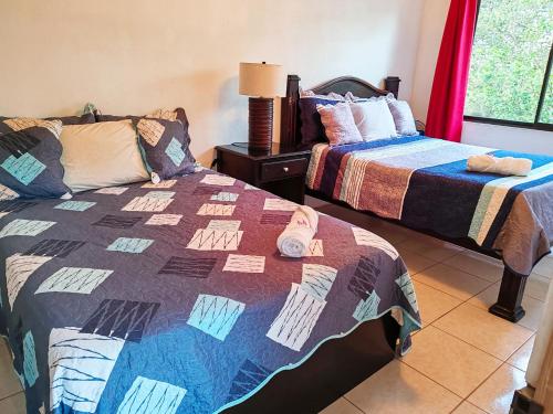 a room with two beds and a table with a lamp at Casa Montañas Nicoyanas in Juan Díaz