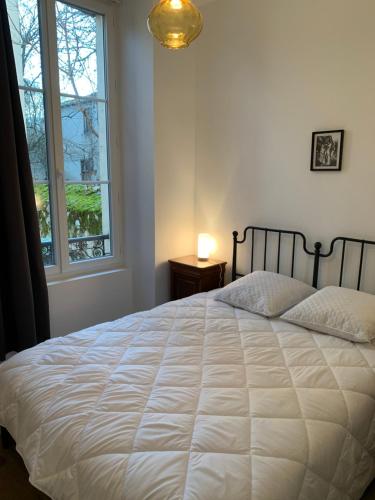 a bedroom with a large white bed with a window at Appartement avec jardin in Loures-Barousse