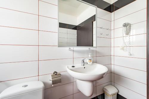 a white bathroom with a sink and a toilet at Domki Letniskowe Bursztynek in Grzybowo