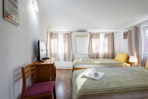 a small bedroom with two beds and a tv at Flowers Grand Hotel Bucharest in Bucharest
