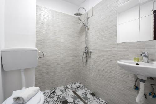 a white bathroom with a toilet and a sink at Flowers Grand Hotel Bucharest in Bucharest
