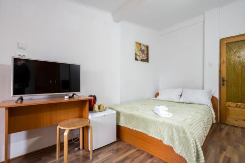 a small bedroom with a bed and a tv at Flowers Grand Hotel Bucharest in Bucharest