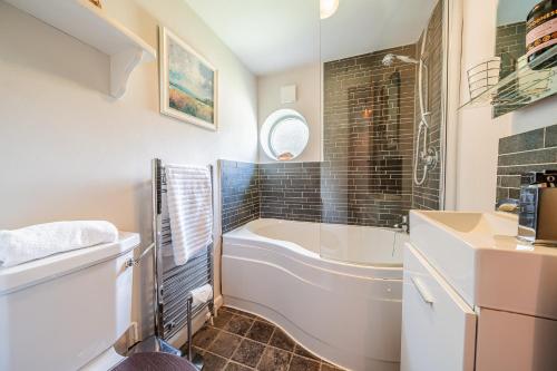 a bathroom with a bath tub and a sink at Beautiful Riverside Cottage with Large Garden, 2BR in Boldre