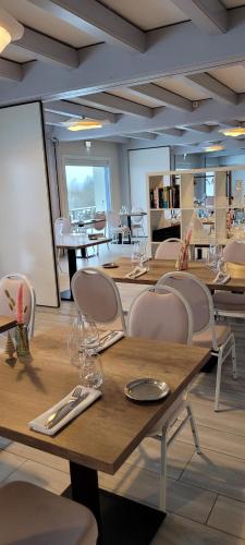 a restaurant with wooden tables and white chairs at Hotel Lou Granva in Grande Riviere