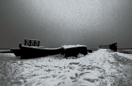 a boat is covered in snow on a pier at Vivaldi Lake House in Meteliai