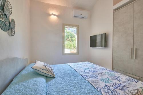 a bedroom with a bed with a blue comforter and a window at Villa Corallo in Costa Rei