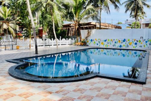 a swimming pool in a courtyard with palm trees at The Travancore Palace Beach Resort in Kovalam