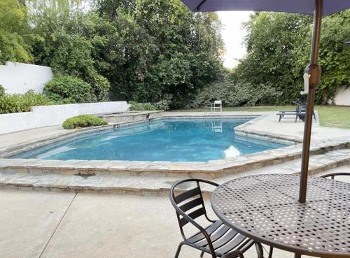 a table with an umbrella next to a swimming pool at Beautiful 4BD and 3BA Pool Jacuzzi Vacation Home in Los Angeles