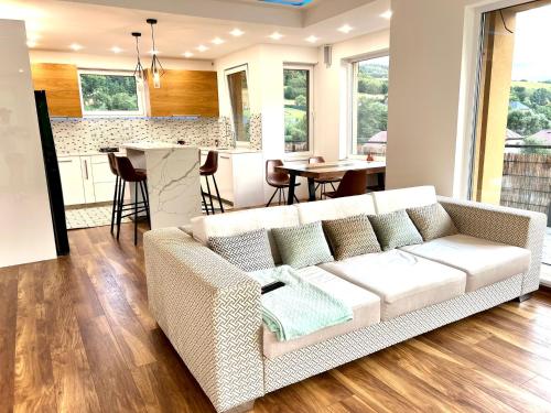 a living room with a white couch and a kitchen at Slnečná vila pod lesom in Horný Vadičov