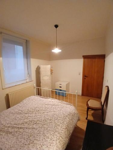 a bedroom with a bed and a window and a chair at Cosy homestay in Quiet historic area in Tienen