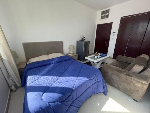 a bedroom with a blue bed and a couch at Heart of Abu Dhabi - New Community Elite Room in Abu Dhabi
