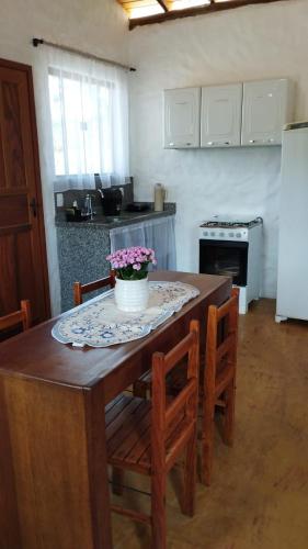 a kitchen with a table and chairs with flowers on it at Chalés do Caminho - Afeto in Ritápolis