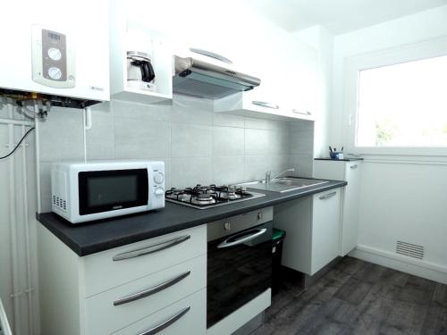 - une cuisine blanche avec un four micro-ondes et un évier dans l'établissement LM86 , CENTRE VILLE , BALCON , AU CALme, à Lorient