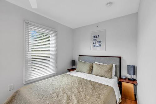 a white bedroom with a bed and two windows at The Central Ave House in Ocean Grove