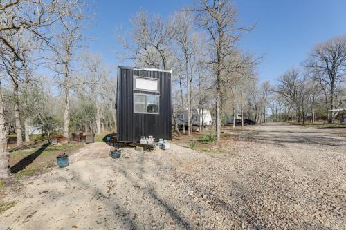 a black tiny house sitting on a dirt road at Hiking and Creek Manor Tiny Home in Forest Retreat in Manor