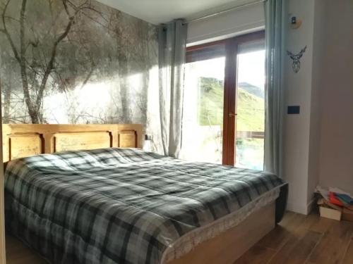 a bedroom with a bed and a large window at Bilocale I cervi a pochi passi dalle piste con vista Mondolè in Prato Nevoso