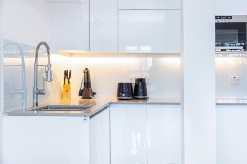 a kitchen with white cabinets and a sink at Harley Street Luxury Apartments by City Relay in London