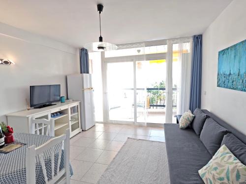 a living room with a couch and a tv at Blanco&Azul - Ocean View Balcony, Pool and Perfect Location in Playa de las Americas
