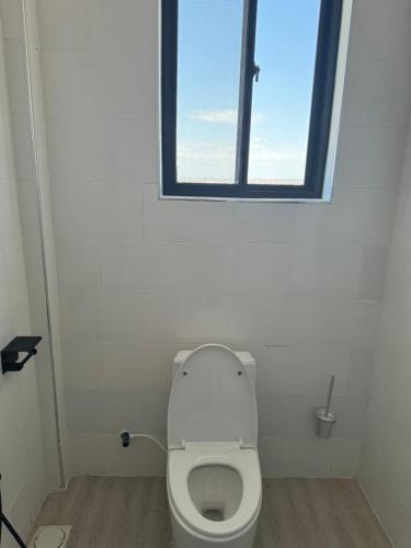 a white bathroom with a toilet with a window at Eastern City Apartments in Dodoma
