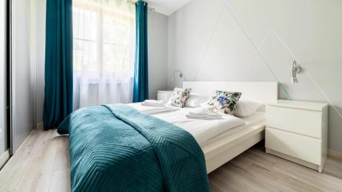 a white bedroom with a bed with a blue blanket at Apartamenty Karpacz in Karpacz