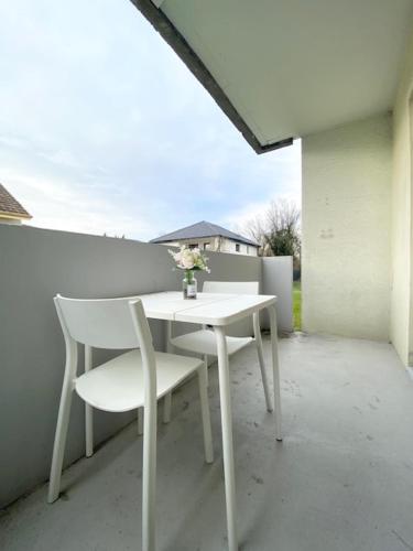 une table et une chaise blanches assises sur un balcon dans l'établissement Studio Clara - proche gare et aéroport, balcon, à Village-Neuf