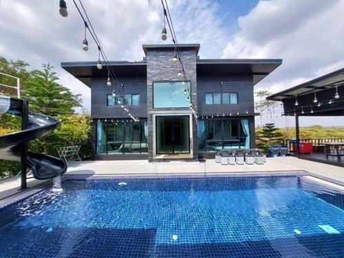 ein Haus mit einem Swimmingpool vor einem Haus in der Unterkunft Wishing Moon Khaoyai Home Chanchaokha Resort in Pong Talong