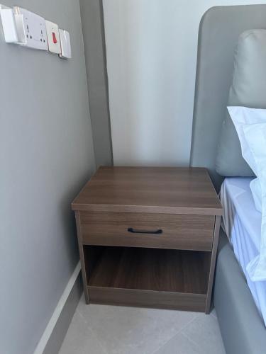 a wooden nightstand next to a bed in a room at Eastern City Apartments in Dodoma