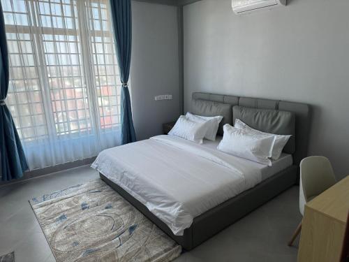 a bedroom with a bed with white sheets and pillows at Eastern City Apartments in Dodoma