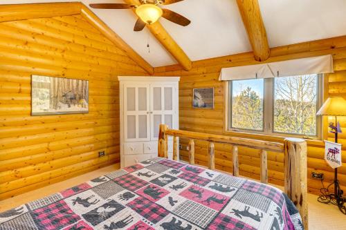 a log cabin bedroom with a bed and a ceiling fan at Private Fishing Pond Mtn-View Home in Florissant! in Florissant